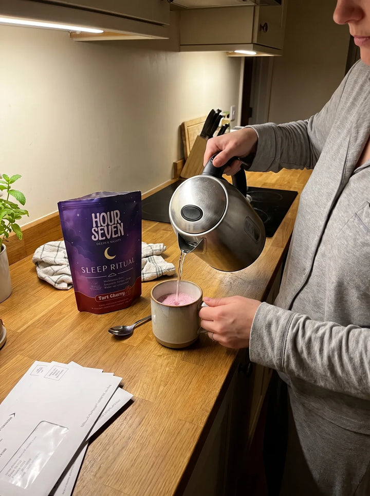 Hot water being poured into a mug beside a pouch of Hour Seven Sleep Ritual