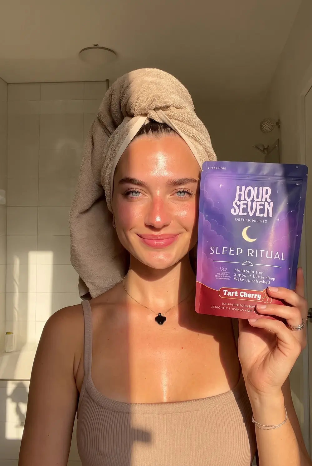 A customer fresh out of the shower holding the Hour Seven pouch